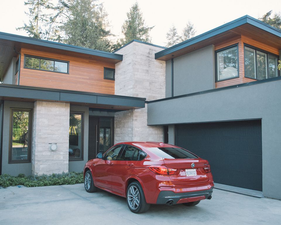 A red SUV parked in front of a modern wood and stone house