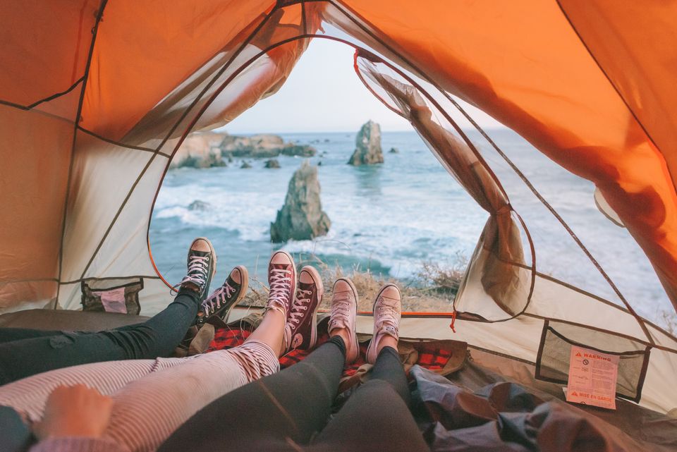 Looking out of an orange tent toward sea stacks and surf