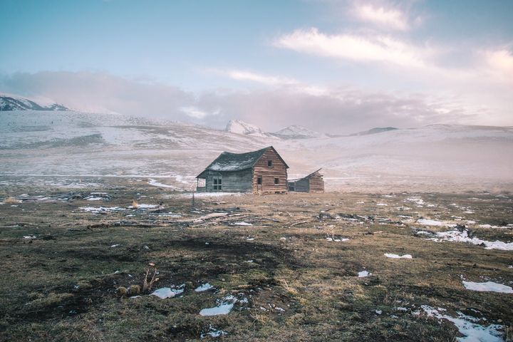 A lone house on a frosty plain under drifting fog